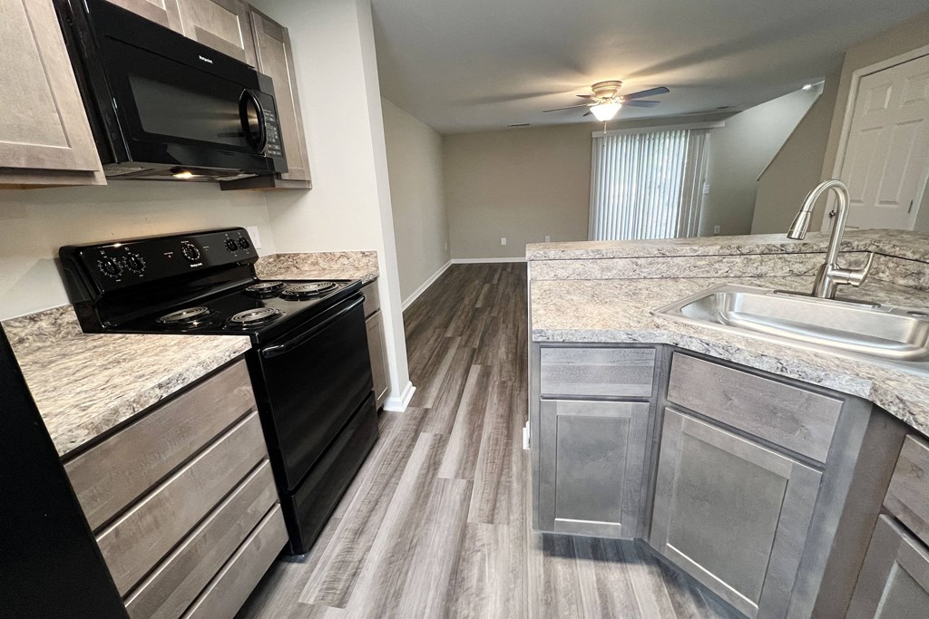 a kitchen with a black stove top oven next to a sink  at Woodhills Apartments, Ohio, 45449
