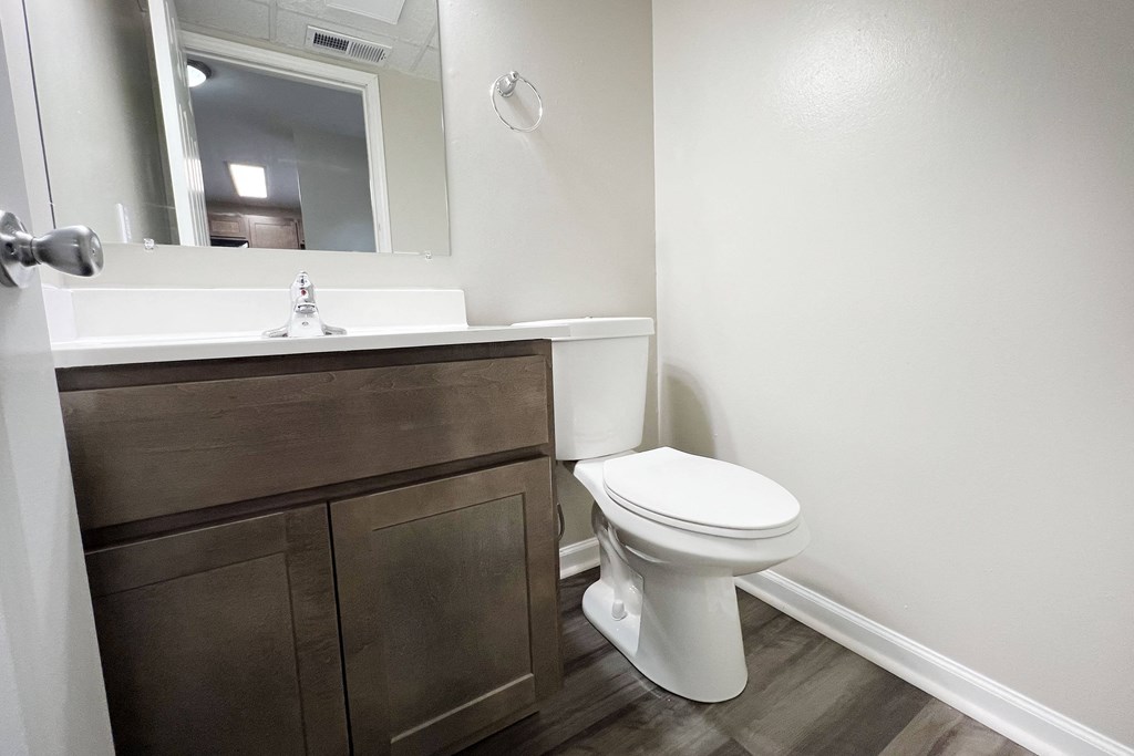 a bathroom with a toilet sink and mirror  at Woodhills Apartments, West Carrollton, 45449