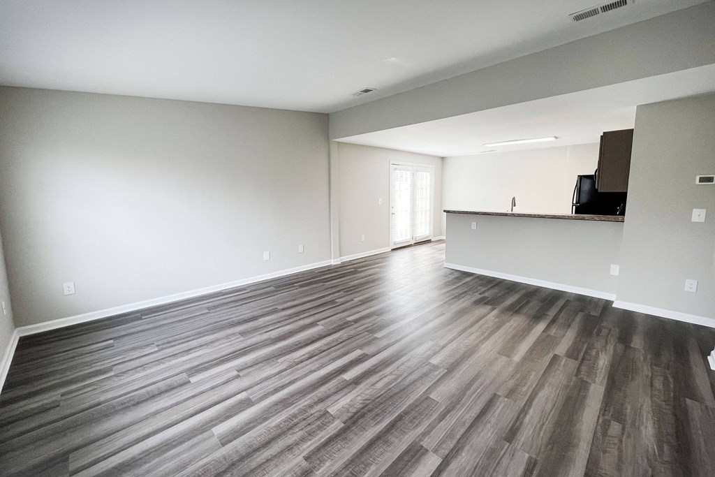 an empty living room with a kitchen in the background  at Woodhills Apartments, West Carrollton, Ohio