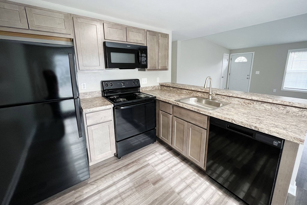 a kitchen with black appliances and wooden cabinets  at Woodhills Apartments, West Carrollton, OH, 45449