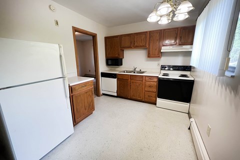 A kitchen with white appliances and wooden cabinets.