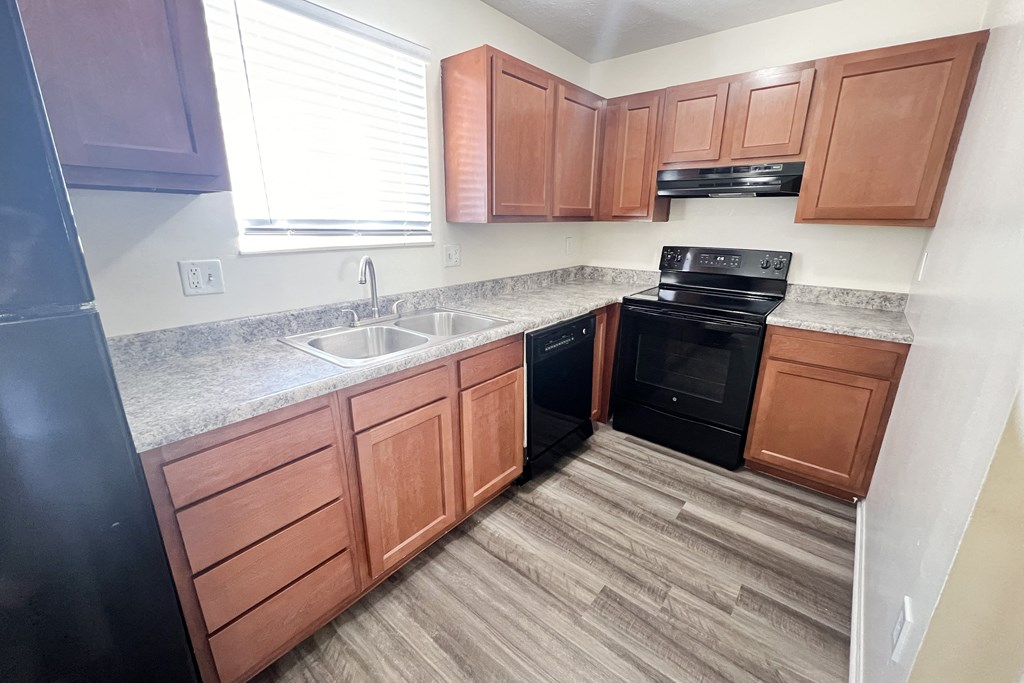 an empty kitchen with wooden cabinets and black appliances at The Villas at Kingswood, West Chester, OH