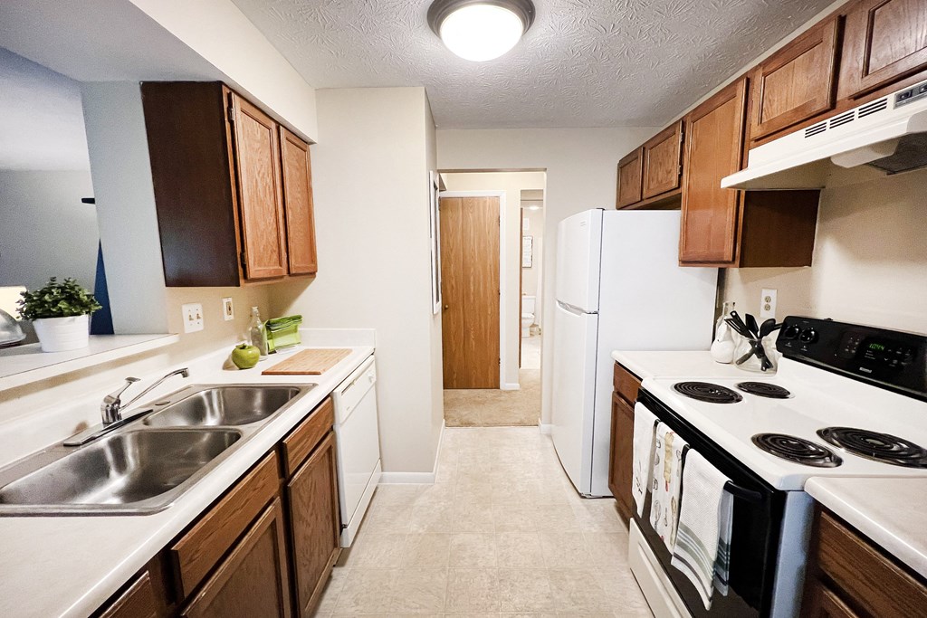 full kitchen with white appliances and wooden cabinets and a white refrigerator at The Vinings Apartments, Cincinnati
