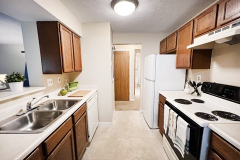 full kitchen with white appliances and wooden cabinets and a white refrigerator at The Vinings Apartments, Cincinnati