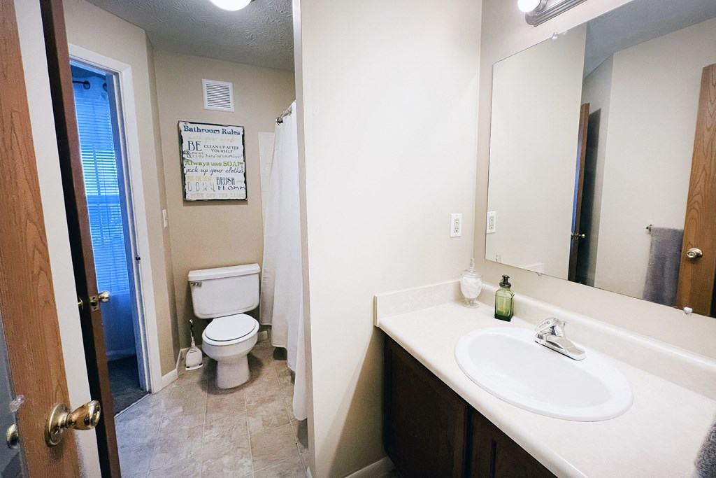 a bathroom with a toilet and a sink and a mirror at The Vinings Apartments, Cincinnati, 45245