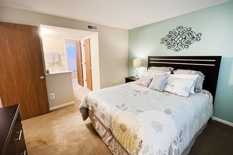 a bedroom with a bed and a door to a bathroom at The Vinings Apartments, Cincinnati, OH, 45245