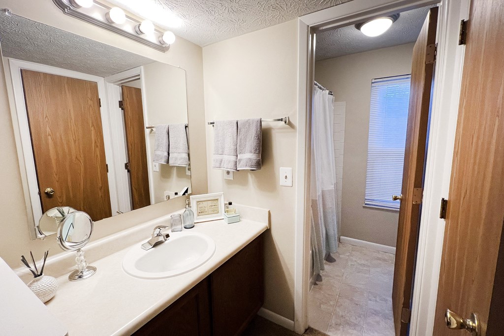 a bathroom with a sink and a mirror and a shower at The Vinings Apartments, Cincinnati, OH