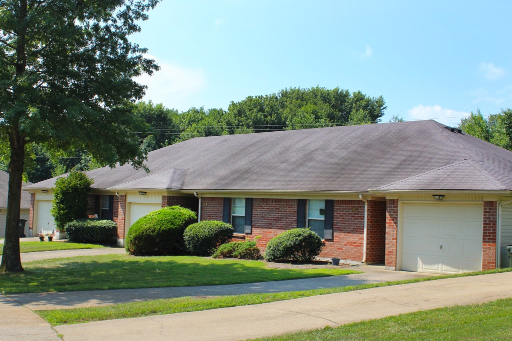 a brick house with a white garage door and a lawn  at Aberdine Place, Kentucky
