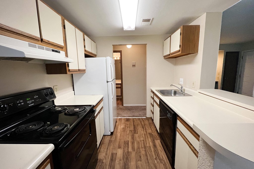 a kitchen with white countertops and a black stove top oven  at Woodhills Apartments, West Carrollton