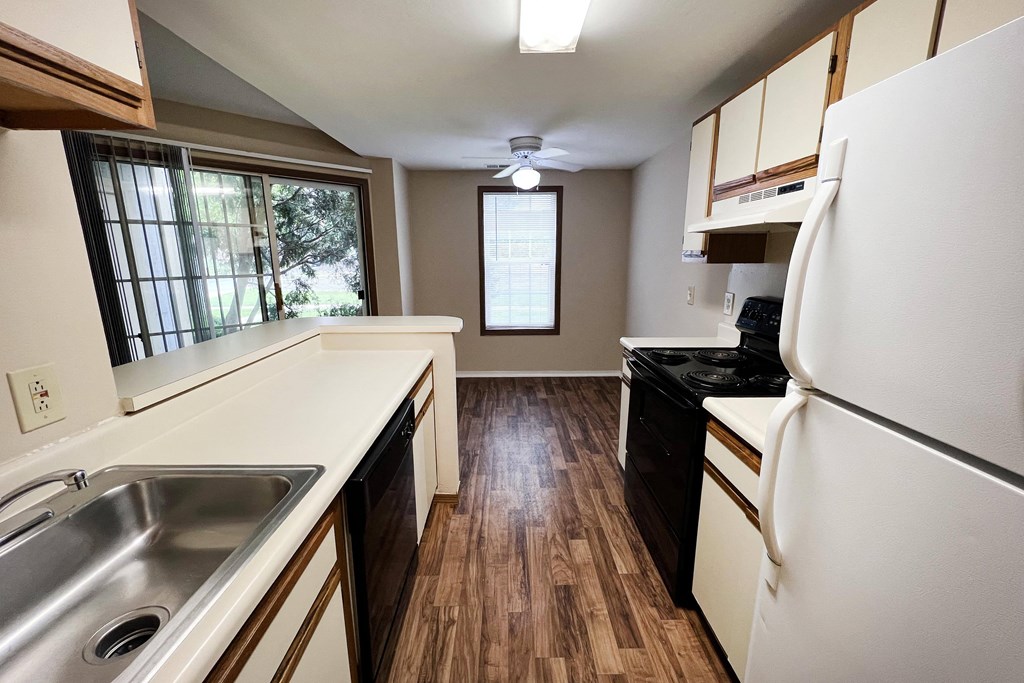 a small kitchen with white countertops and black appliances  at Woodhills Apartments, Ohio