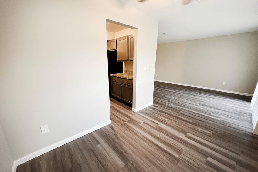 a bedroom with hardwood flooring and a kitchen in the background