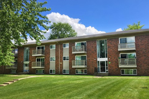 A red brick building with a green lawn in front.