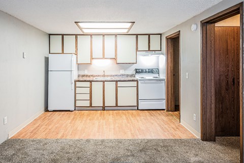 A kitchen with a white refrigerator, white oven, and white cabinets.