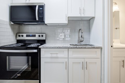 A black microwave oven is mounted above a black stove in a kitchen.