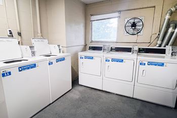 A row of white washing machines with blue labels on them.