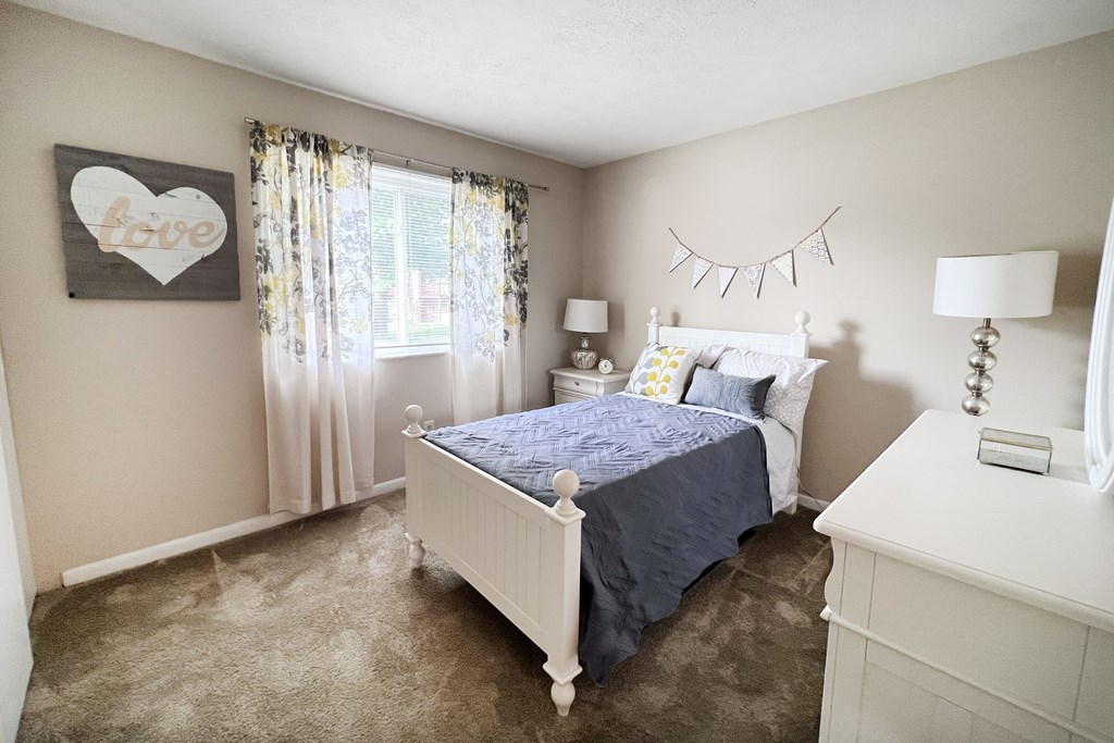 A bedroom with a white bed and a blue bedspread.