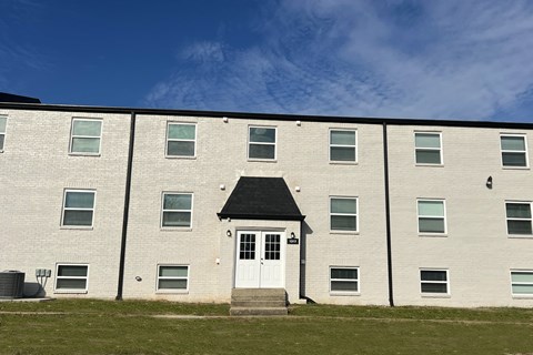 A white building with a black roof and a white door in the center.