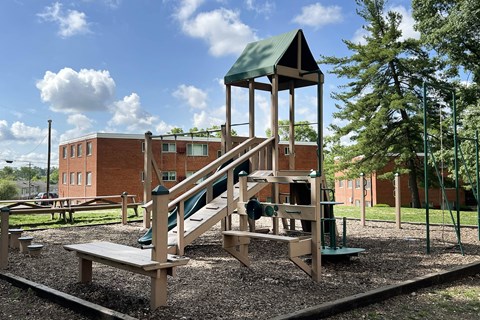 a playground with a slide and a tower with a building in the background at Crown Court Apartments, Kentucky, 41042