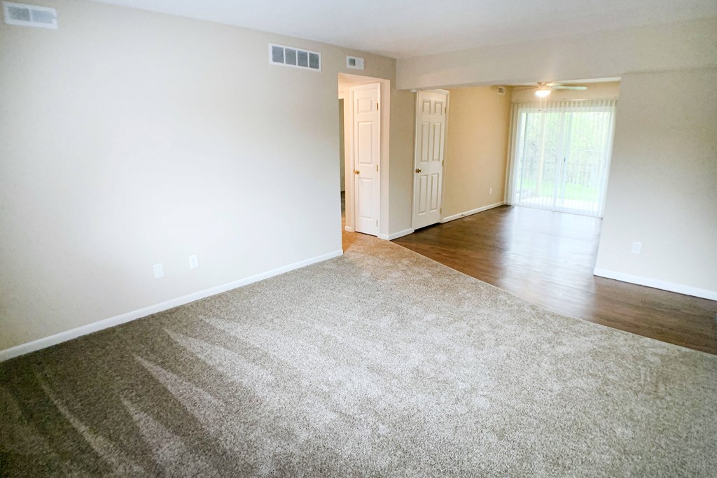 A room with a carpeted floor and a door leading to another room.