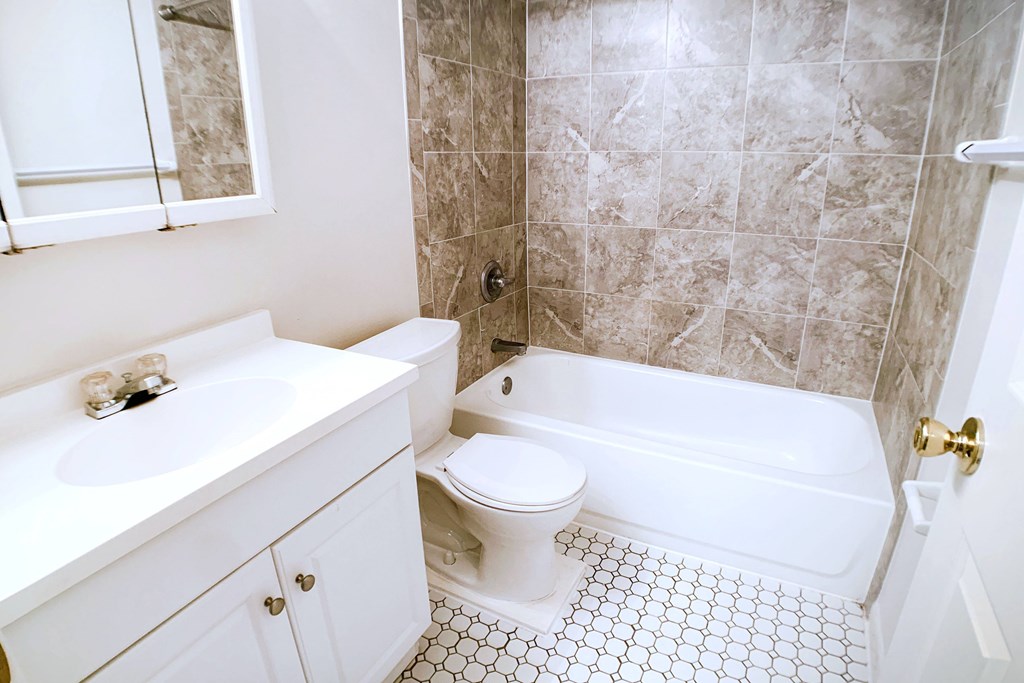 A white bathroom with a tiled floor and a marble wall.
