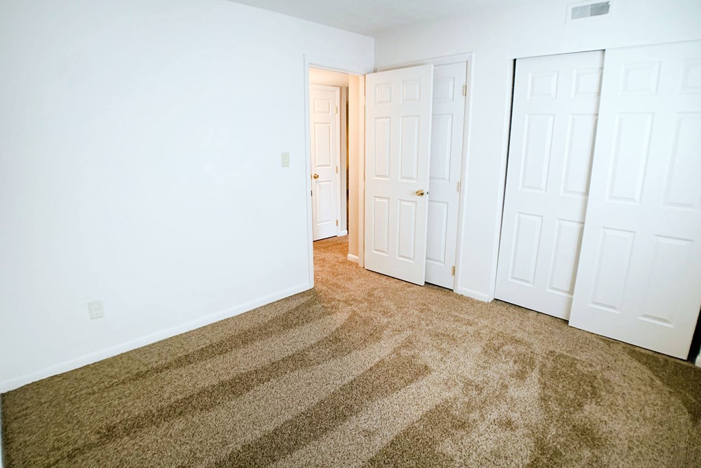 A room with a carpet and three doors.