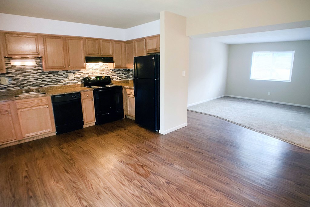 A kitchen with black appliances and wooden floors.
