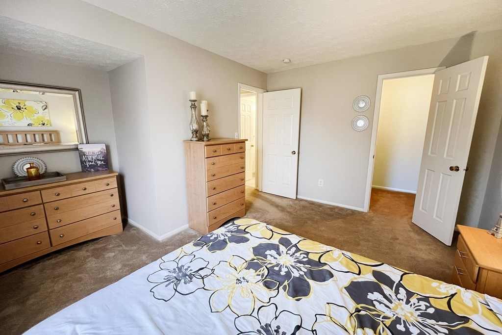a bedroom with a bed and dressers and a closetat Revere Village Apartments, Ohio, 45458