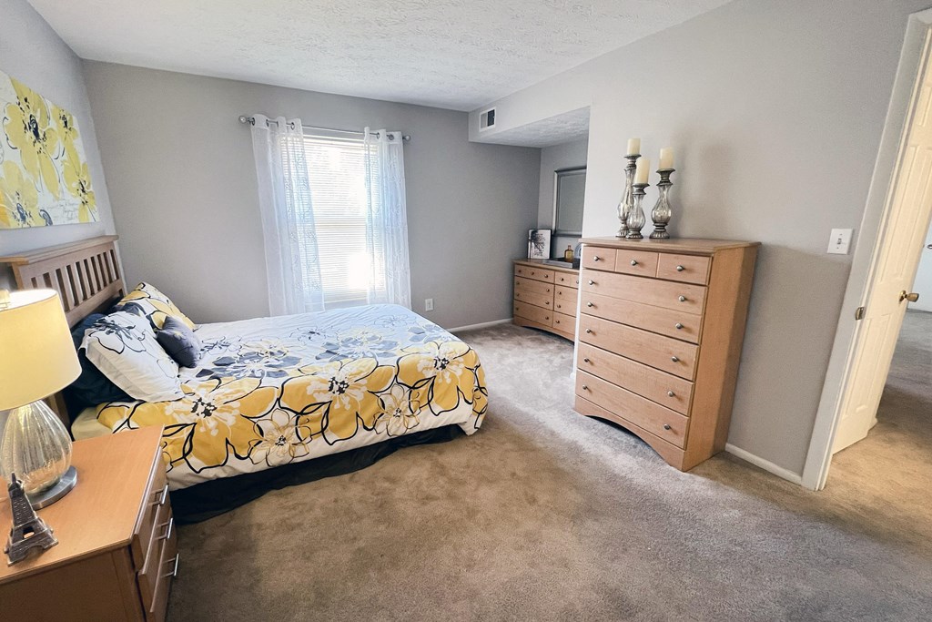 a bedroom with a bed and a dresser in itat Revere Village Apartments, Centerville