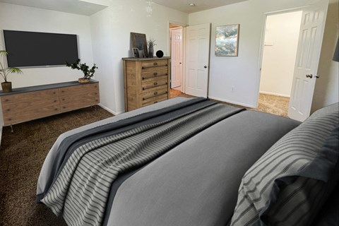 the master bedroom has a large bed and a tvat Revere Village Apartments, Ohio, 45458