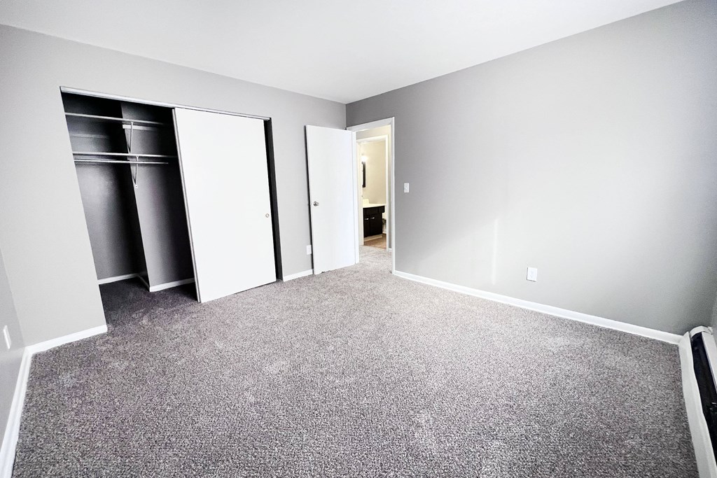 A room with a grey carpet and white walls with a door and a wardrobe.