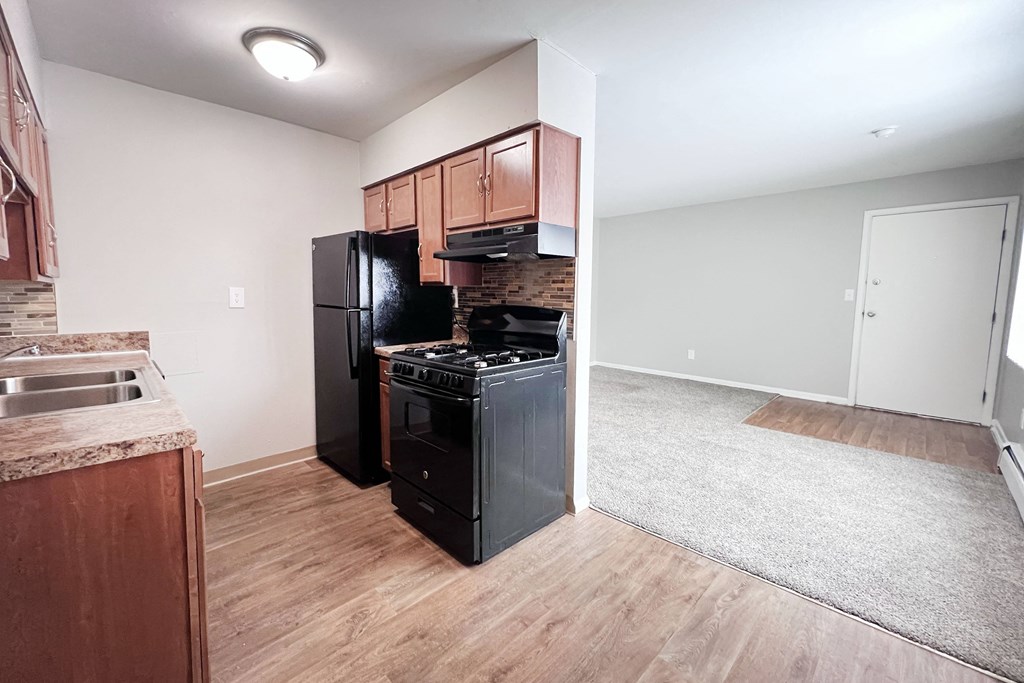 A kitchen with black appliances and wooden cabinets.