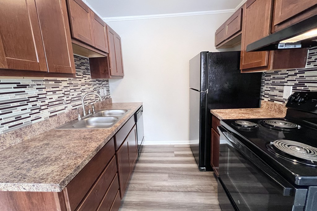 A kitchen with a black refrigerator and a granite countertop.
