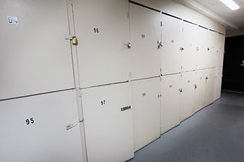 A series of white lockers numbered from 95 to 99 are lined up in a room.