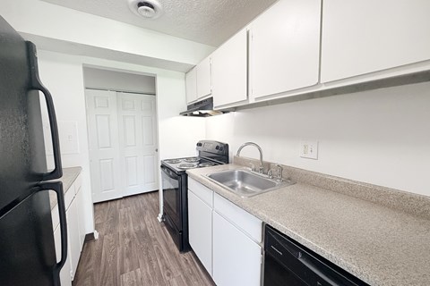 A kitchen with black appliances and white cabinets.