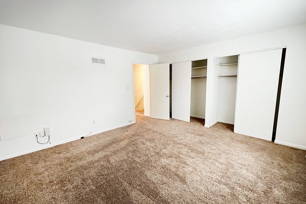 an empty room with white walls and carpet and closet doors at Walnut Creek Townhomes, OH 45236