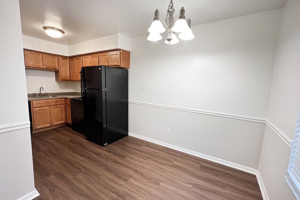 an empty kitchen with a black refrigerator and wooden cabinets at Walnut Creek Townhomes, Cincinnati