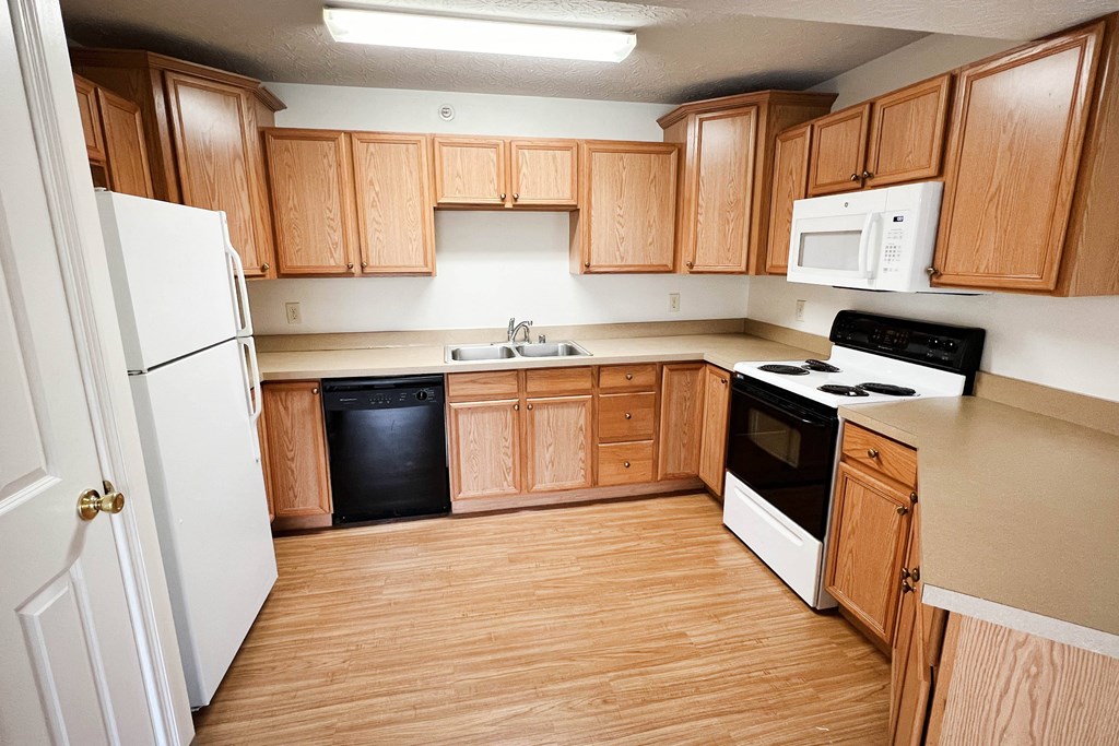 an empty kitchen with wooden cabinets and white appliances  at Walton Ridge Apartments, Walton, Kentucky