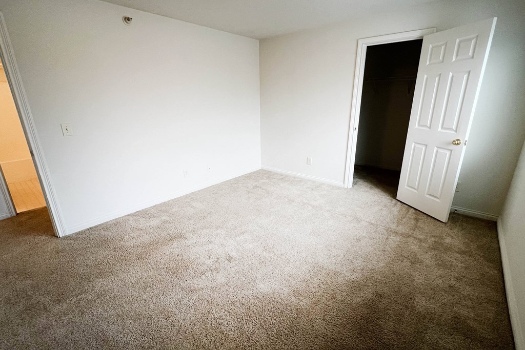 an empty room with a carpeted floor and a white door  at Walton Ridge Apartments, Walton