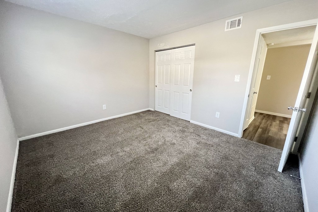 an empty living room with carpet and a door to a bedroom at Revere Village Apartments, Centerville, OH, 45458