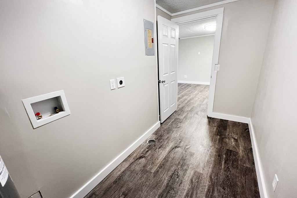 an empty room with white walls and a white door and a hallway with wood floors at Wentworth Estates Apartments, Florence, KY