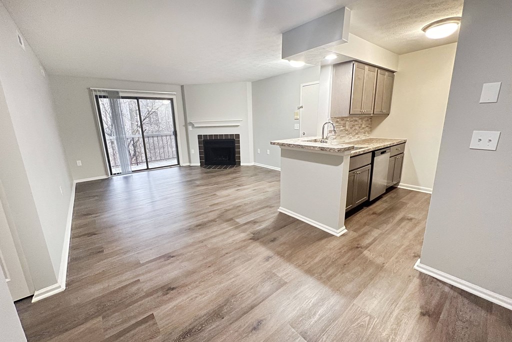 an empty living room with a kitchen and a fireplace  at Deercross Apartments, Cincinnati, 45236