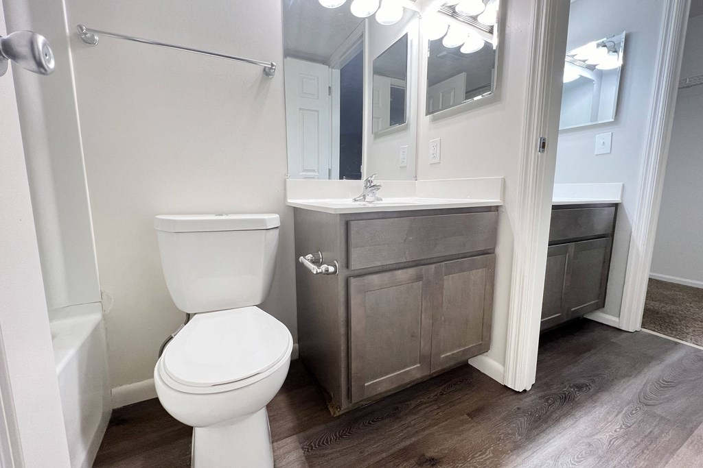 a bathroom with a toilet and a sink and a mirror  at Deercross Apartments, Ohio