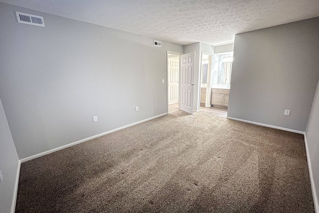 an empty living room with carpet and a door to a bathroom  at Deercross Apartments, Cincinnati