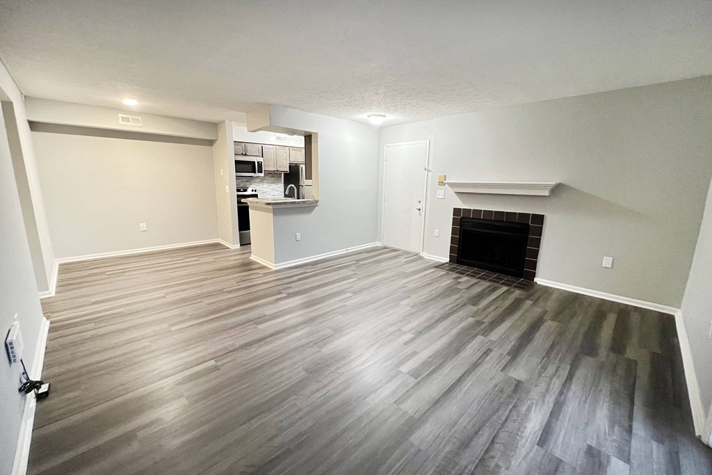 an empty living room with a fireplace and wooden floors  at Deercross Apartments, Cincinnati