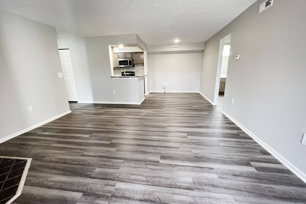 an empty living room with wood flooring and a kitchen  at Deercross Apartments, Cincinnati