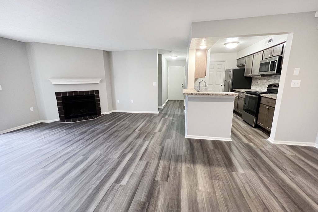 an empty living room with a fireplace and a kitchen  at Deercross Apartments, Cincinnati