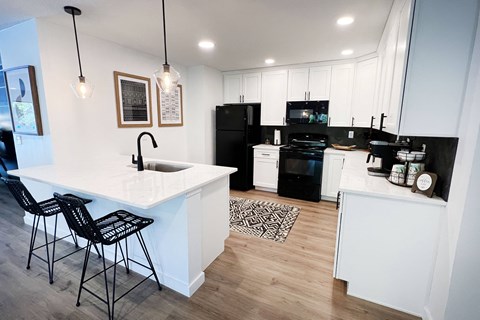 a kitchen with white cabinets and black appliances