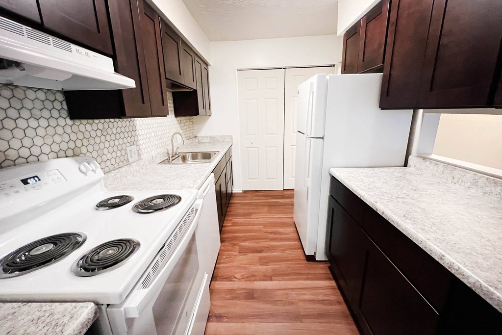 a kitchen with white appliances and brown cabinets  at Concord Woods Apartments, Ohio