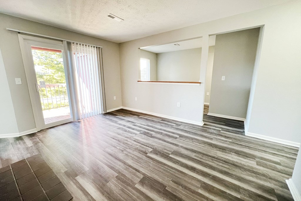 an empty living room with wood flooring and sliding glass doors  at Deercross Apartments, Cincinnati