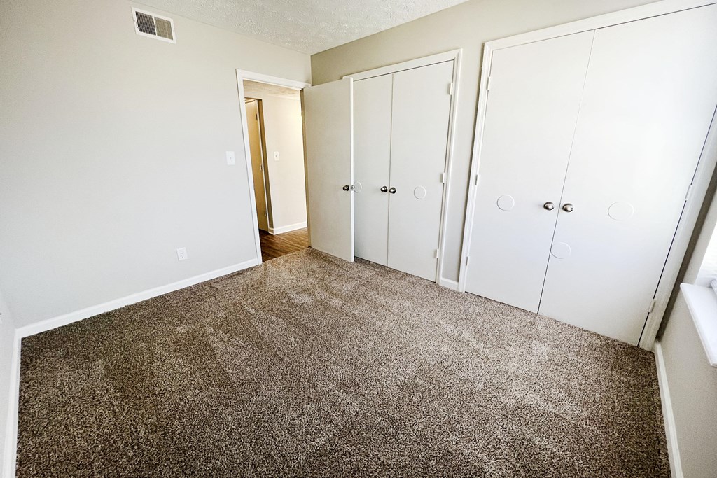 a bedroom with a carpeted floor and three closets at 450 on Keeneland, Kentucky